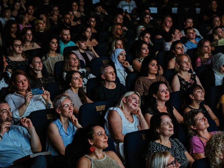 Absolvent:innen warten im Kinosaal auf die Zeugnisübergabe.