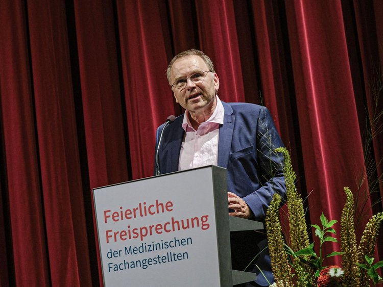 Studiendirektor Jürgen Barning, stellvertretender Schulleiter der Rahel-Hirsch-Schule, spricht zu den Absolvent:inen und Gästen.