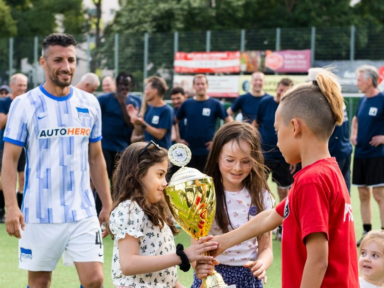 Drei Kinder: Zwei Mädchen und ein Junge mit dem Wanderpokal