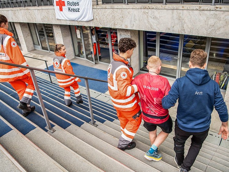Rennarzt und Mitarbeitende vom Roten Kreuz mit einem verletzten Läufer.