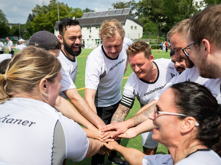 Teamgeist: Spieler stehen im Kreis und legen die Hände aufeinander, um sich vor dem Fußballpiel zu motivieren.