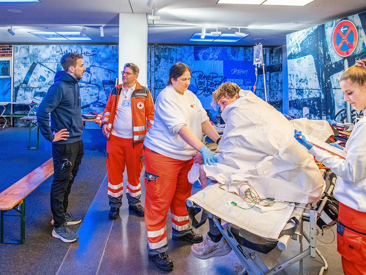 Rennarzt im Gespräch mit Kollegen vom Deutschen Roten Kreuz, Läufer mit Wärmedecke