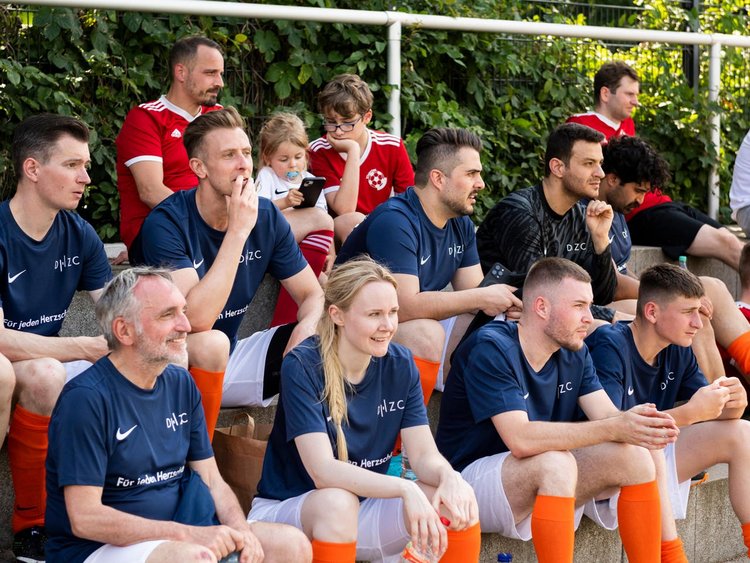 Spieler sitzen am Spielfeldrand und beobachten die anderen Mannschaften.