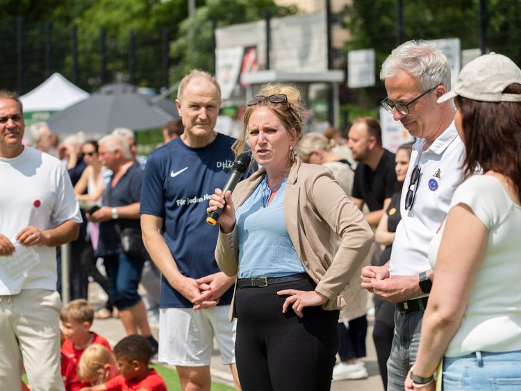 Vier Menschen eröffnen ein Fußballturnier, eine Frau hält ein Mikrofon.