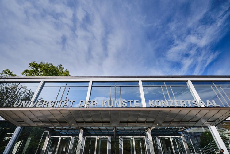 Blauer Himmel spiegelt sich in der Fassade des Konzertsaals der Universität der Künste Berlin