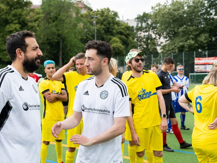 Fußballspieler verschiedener Mannschaften warten auf dem Platz.